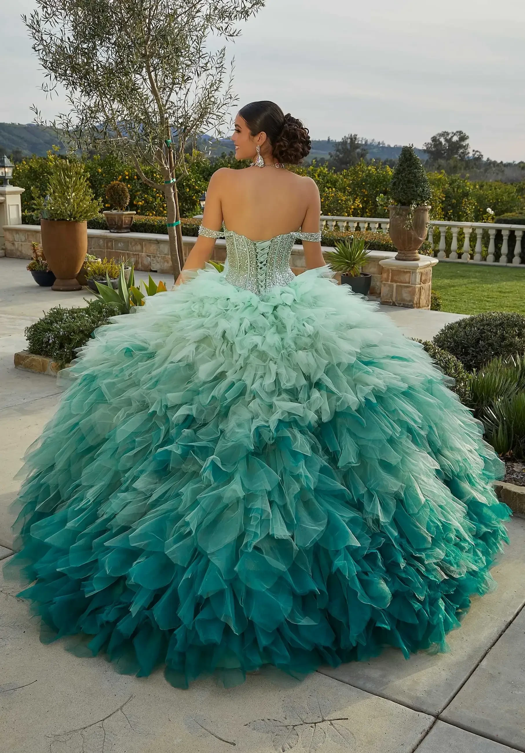 Model is wearing a light green quinceanera ball gown with exposed boning and off the shoulder sleeves