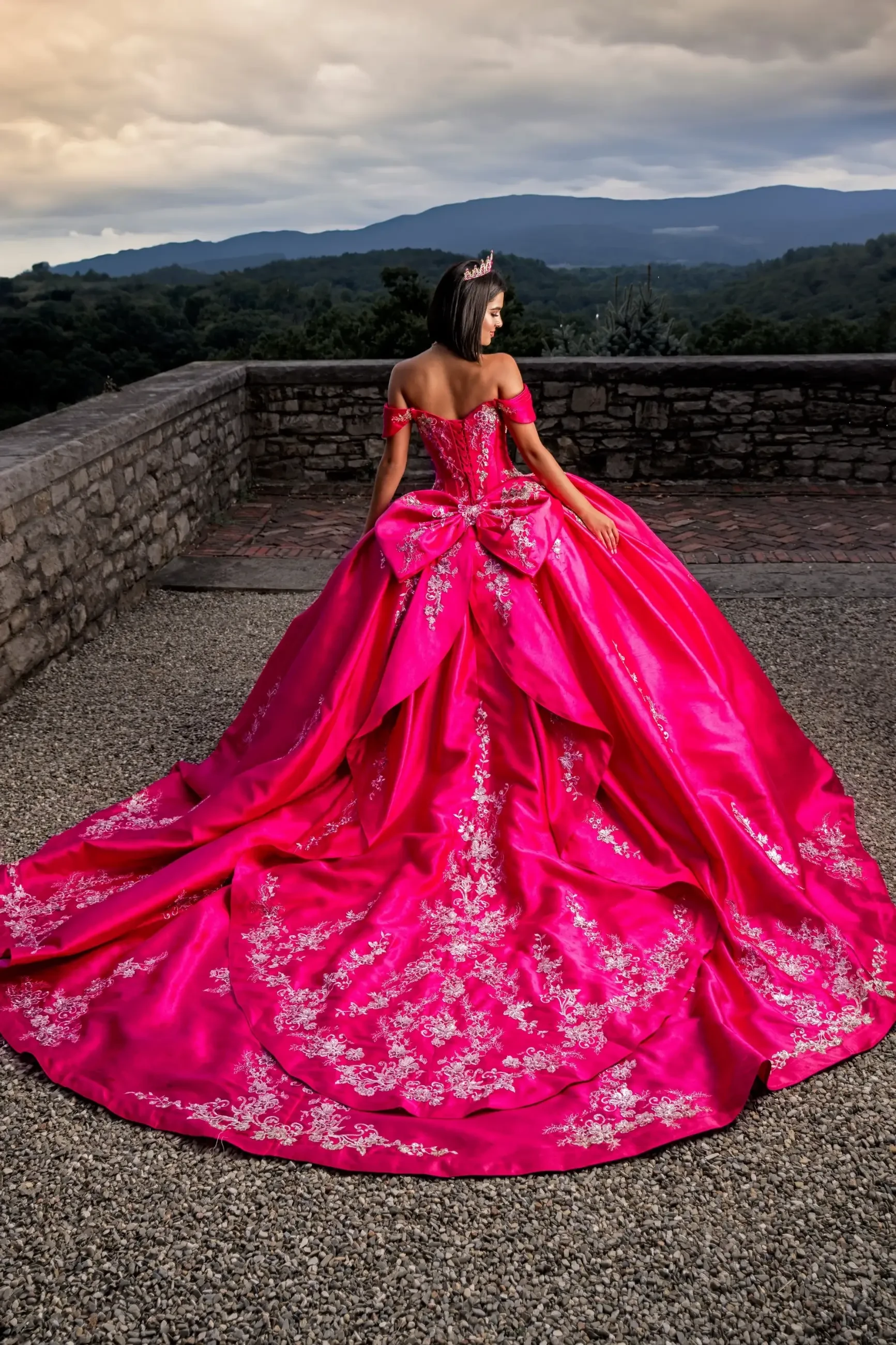 Model is wearing a hot pink ball gown quinceanera dress with off the shoulder sleeves and a strapless bodice